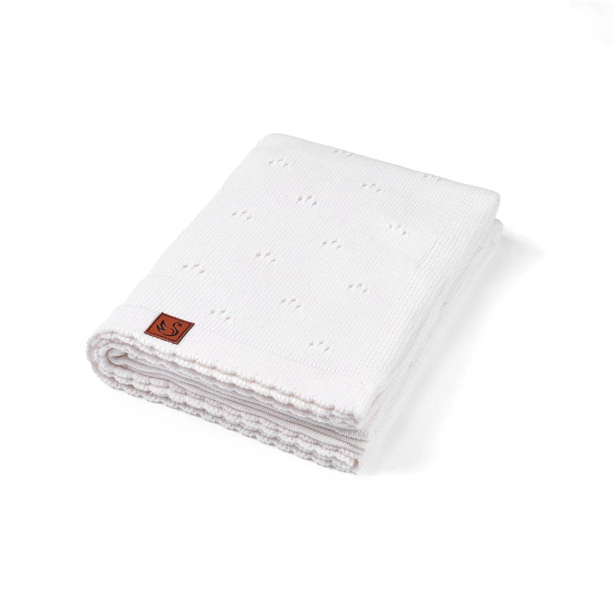 Pointelle baby knit blanket in white, folded with textured eyelet pattern and corner tag.