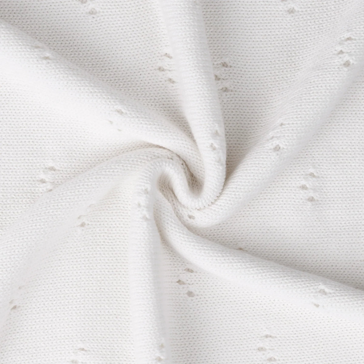 Pointelle baby knit blanket close-up with white textured eyelet dots and soft draped folds.