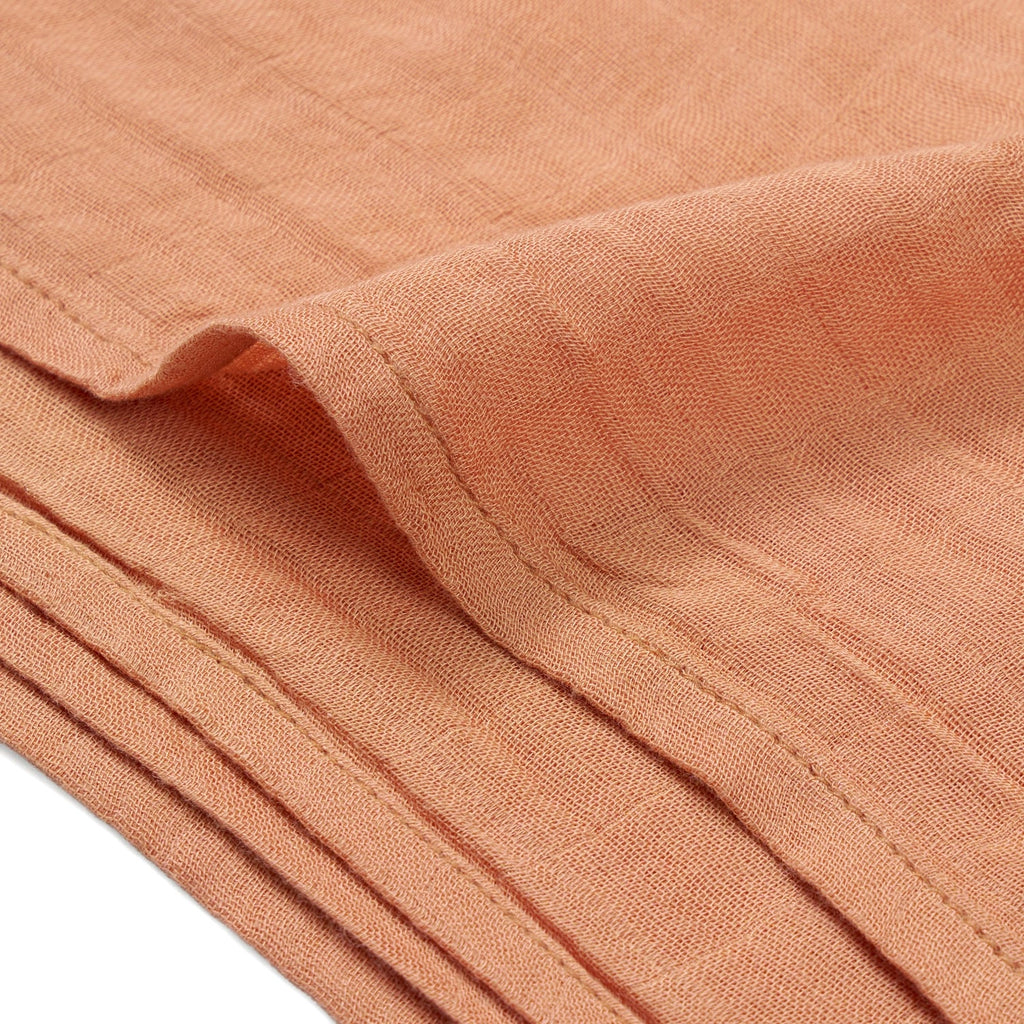 Terra cotta muslin swaddle blanket edge with stitched hem and soft textured weave