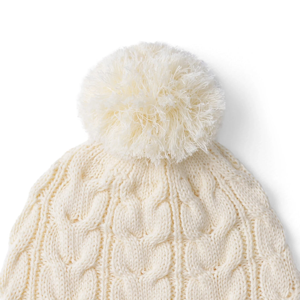 Cream cable-knit pom beanie with thick textured cables and fluffy pom