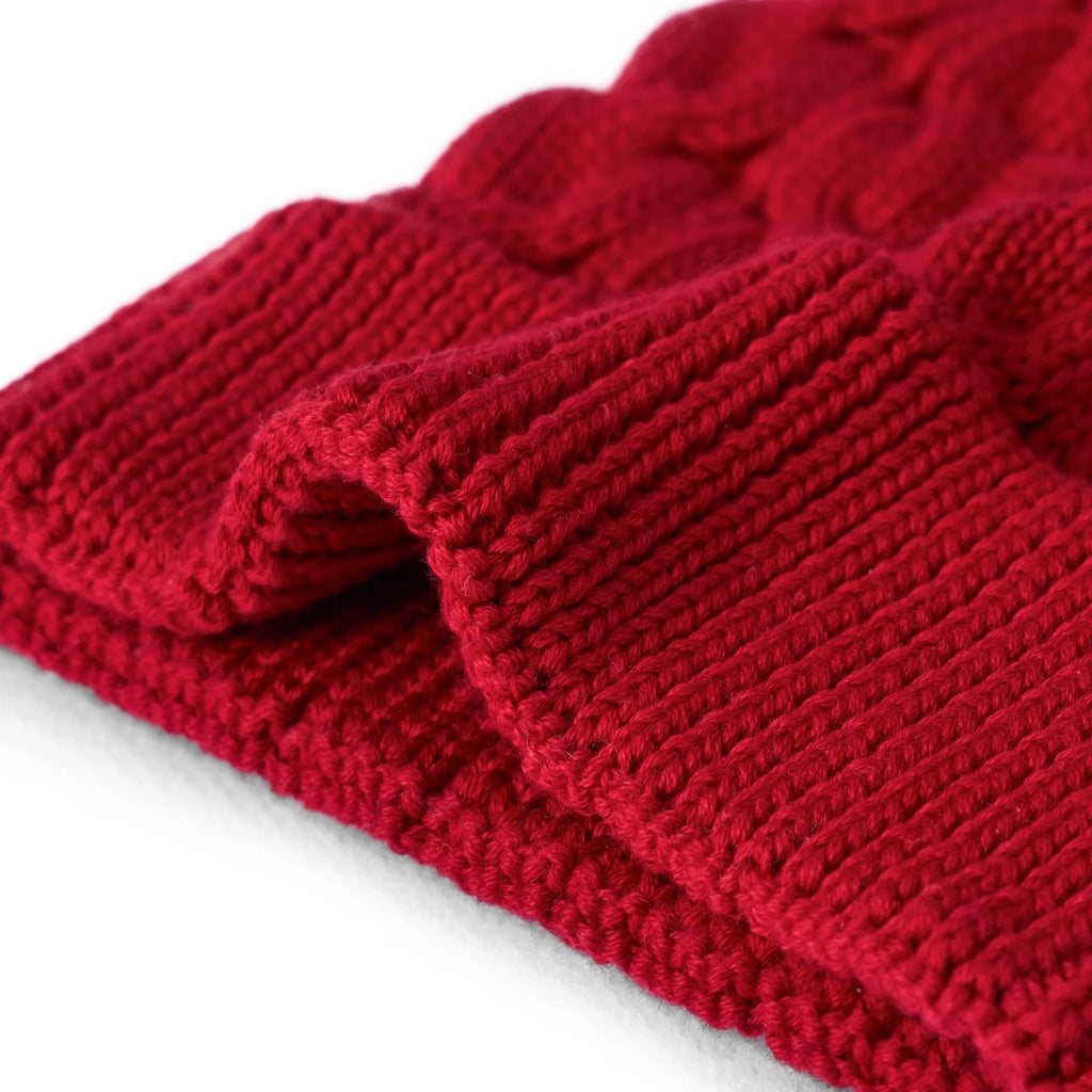 Red cable knit pom beanie fabric texture close-up on folded cuff
