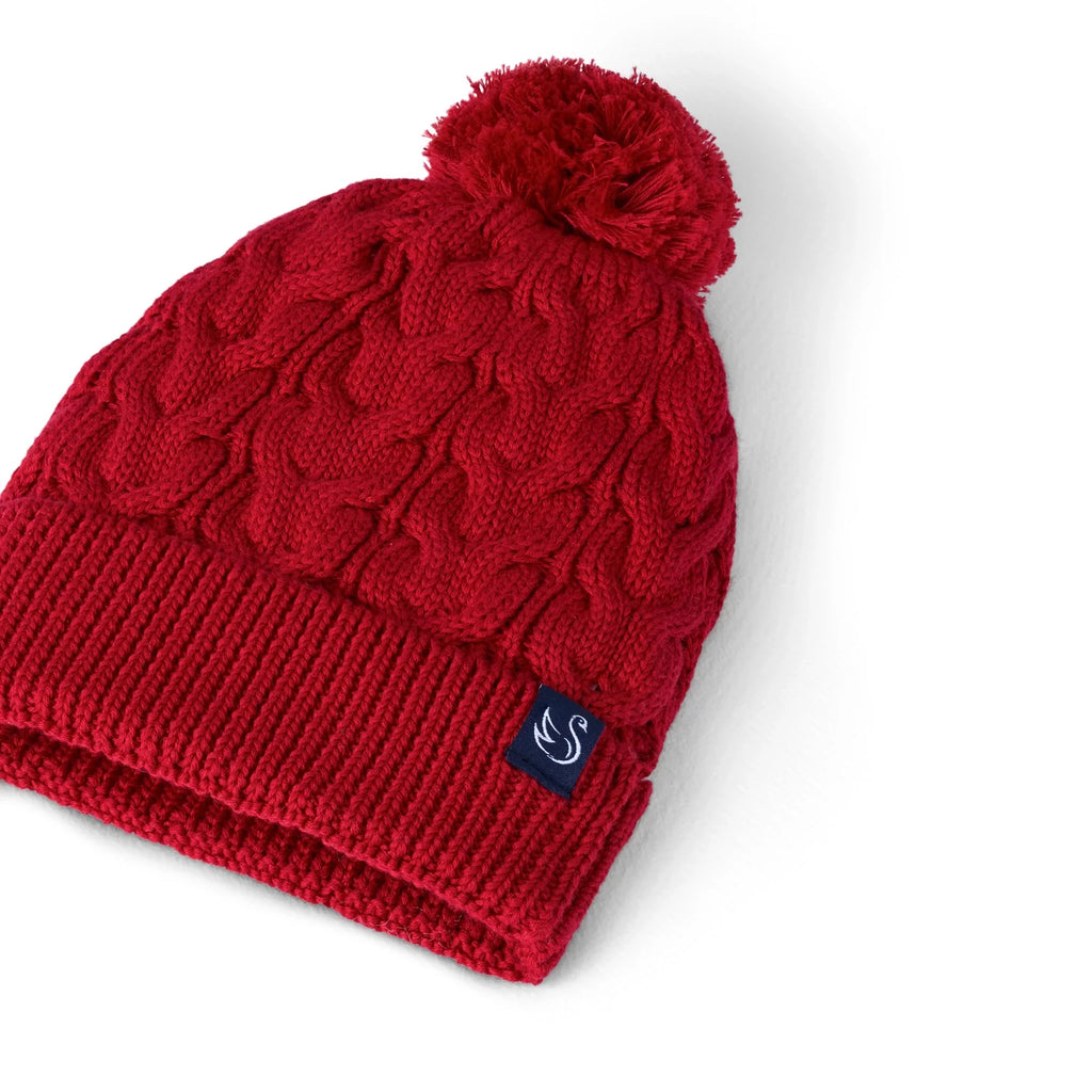 Red cable knit pom beanie angled view with ribbed cuff and side logo patch