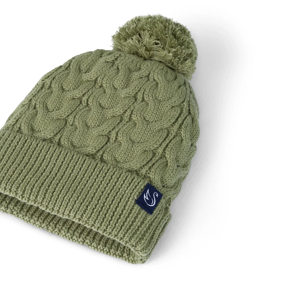 Sage green cable-knit pom beanie with pom top and navy logo patch, side view