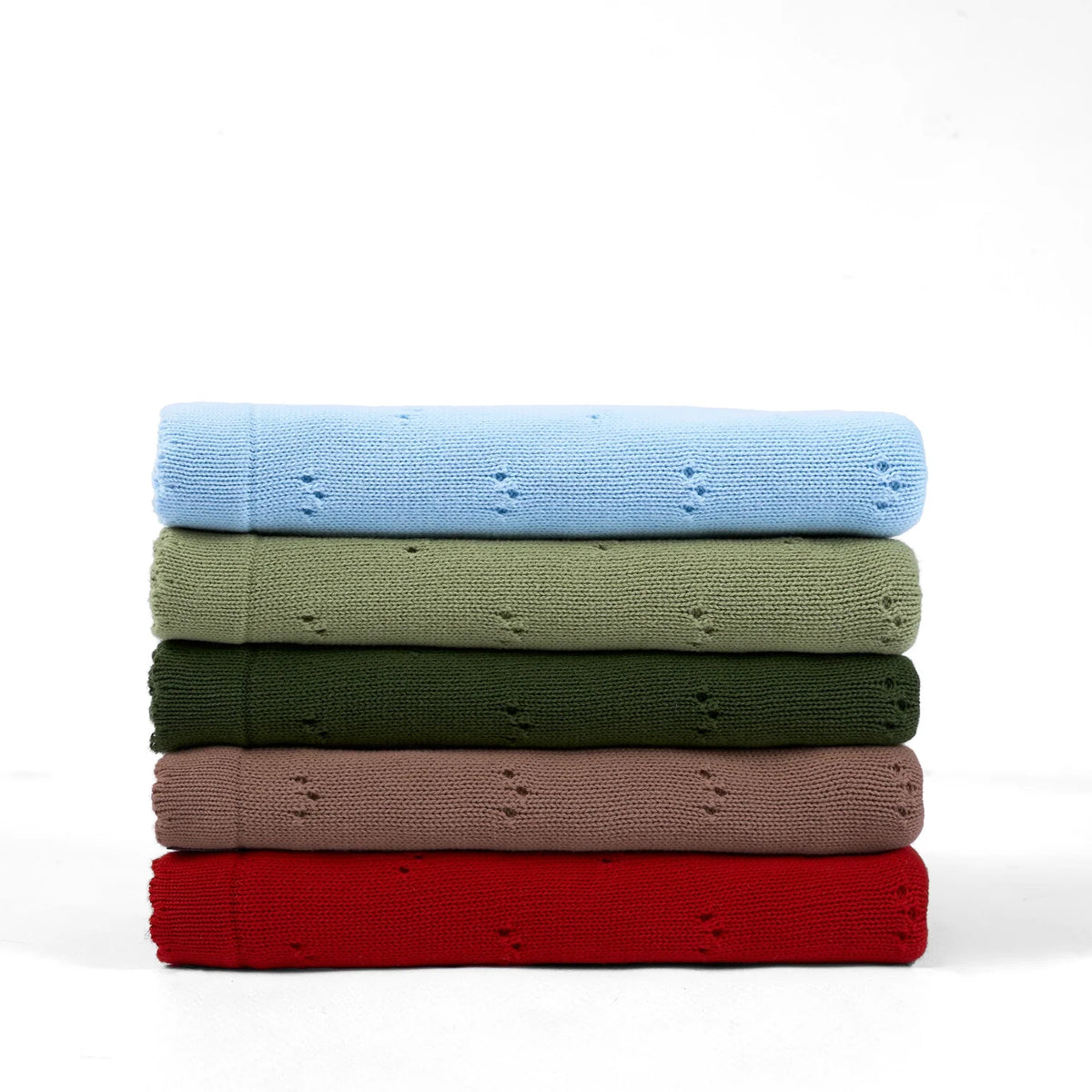 Folded baby knit blankets stack in several colors; forest green pointelle blanket shown