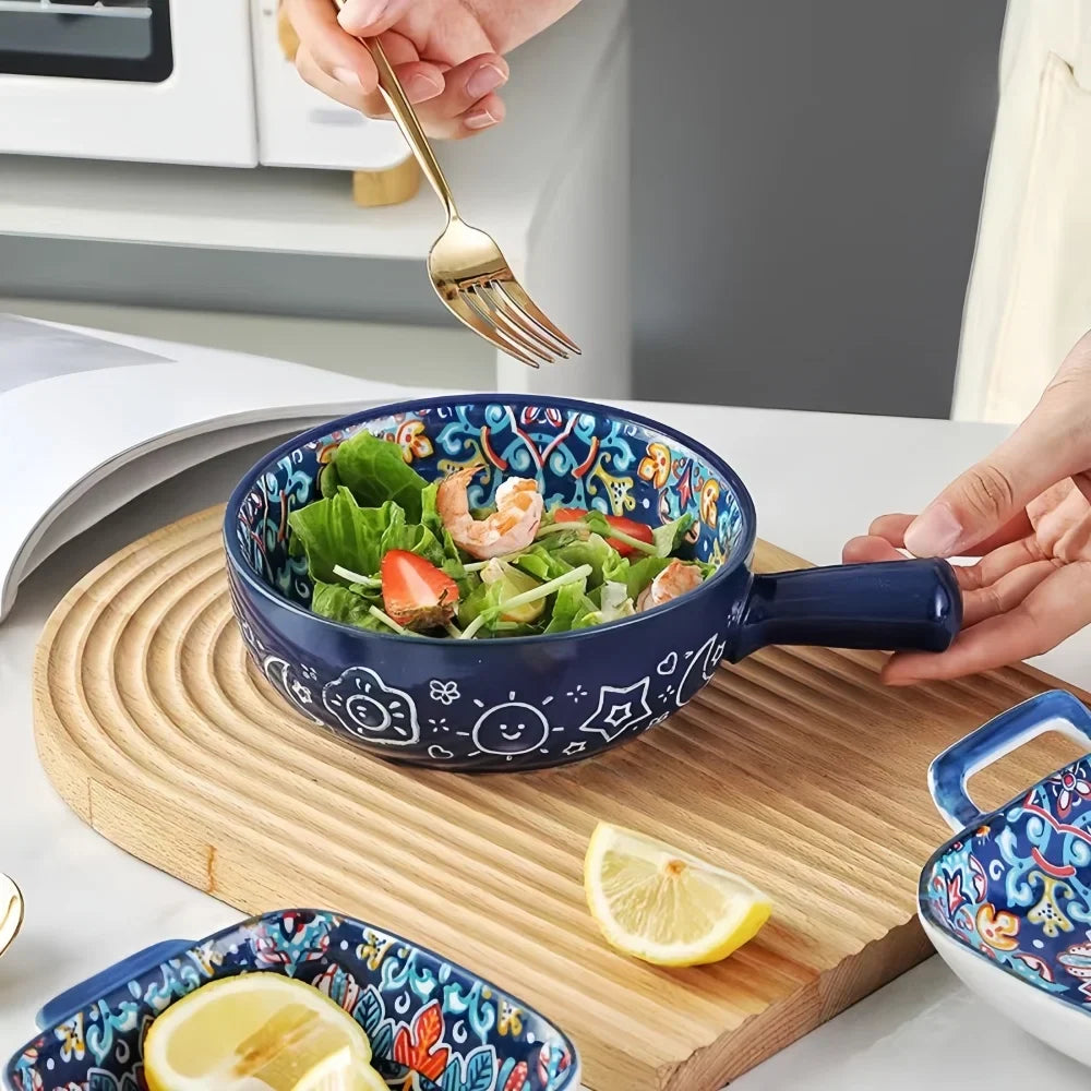 Ceramic salad bowl with blue floral rim, filled with salad, held at the handle