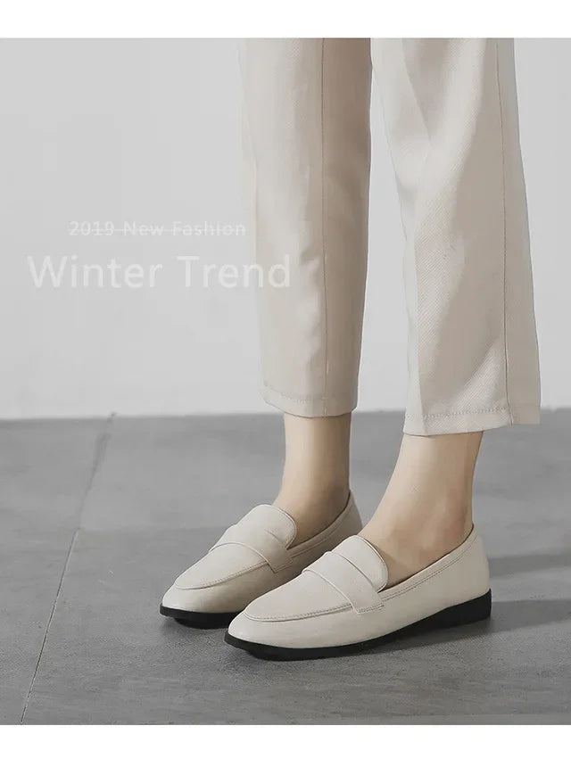 Light beige slip-on loafers with rounded toe, worn with cream pants