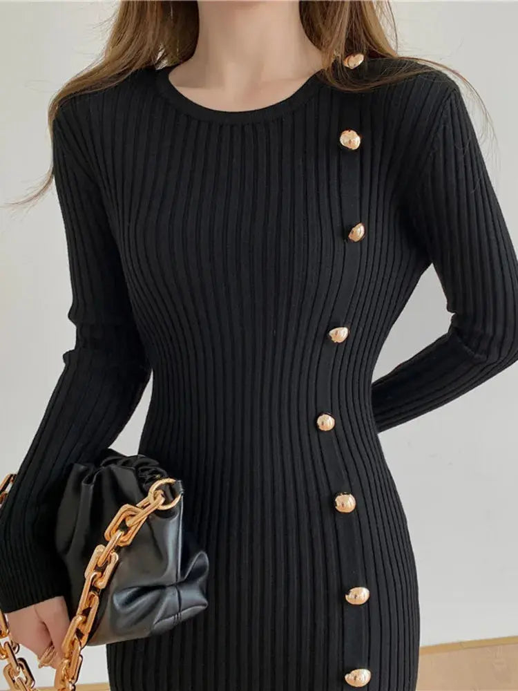 Black ribbed knit sweater dress with round neck, long sleeves, and gold button trim.