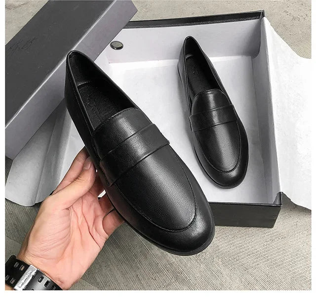 Women’s black leather slip-on loafers, rounded toe, low flat sole.