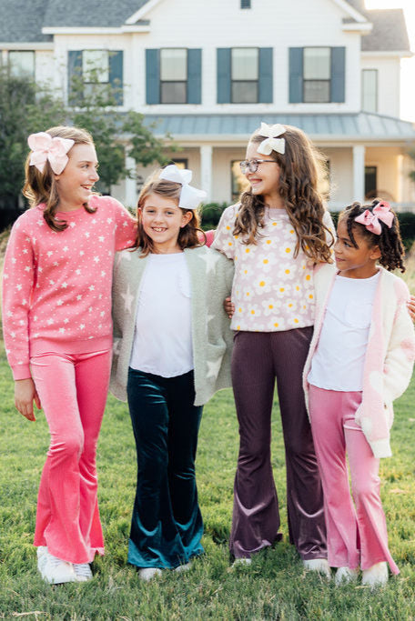 Light pink heart cozy cardigan on child in group, fuzzy white knit with light pink heart print.