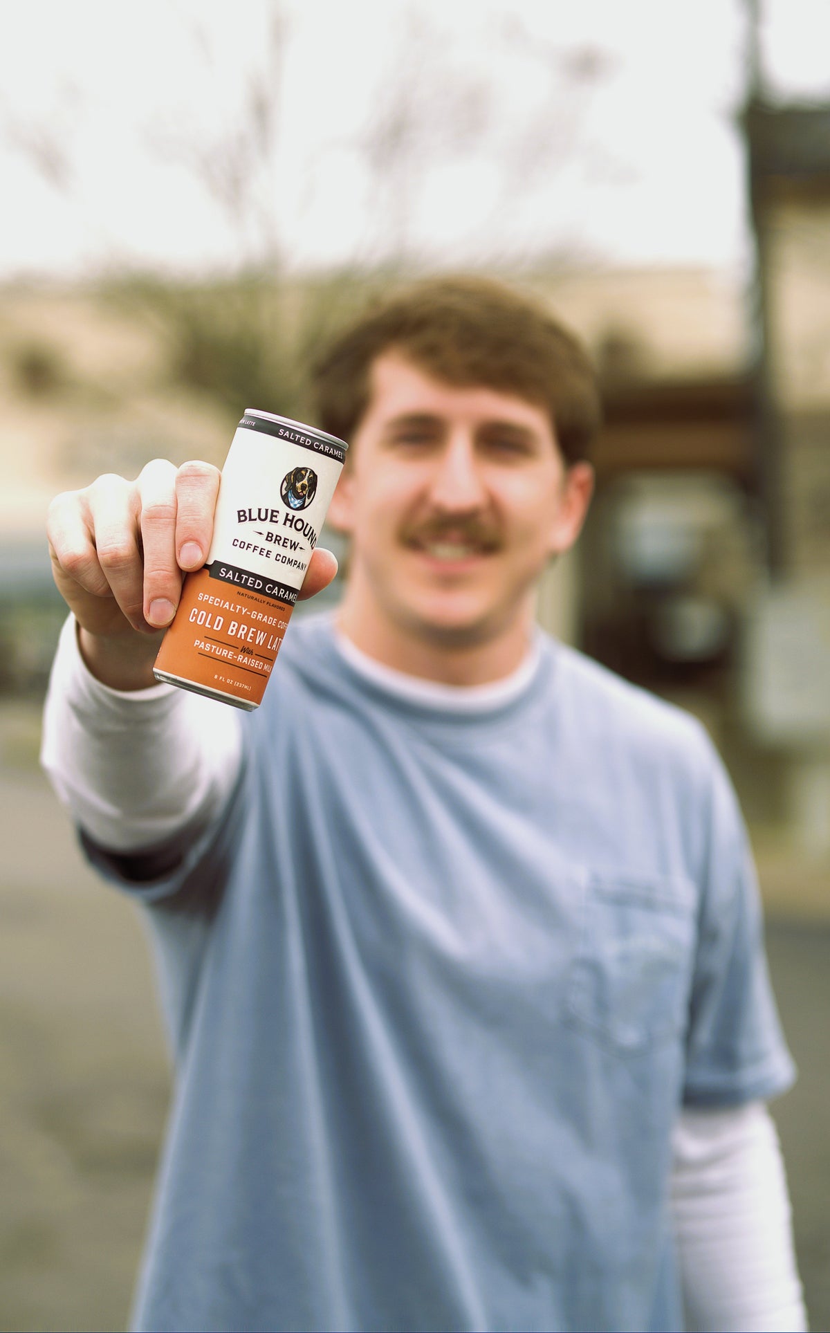 Orange-labeled coffee mug held in hand outdoors