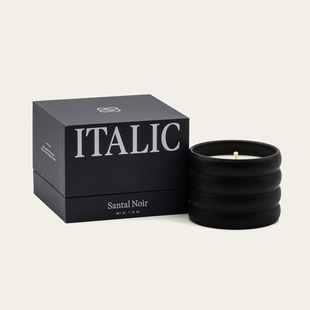 Santal Noir soy wax ceramic candle with lit wick in black ridged holder
