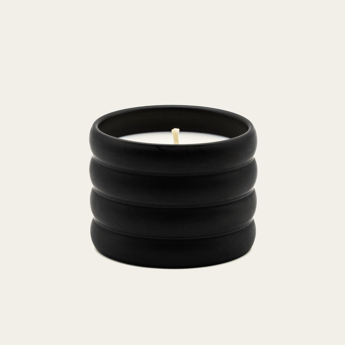 Black ceramic soy wax candle with lit wick, ridged container