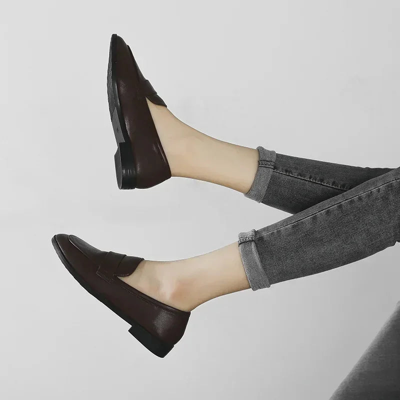 Dark brown slip-on loafers with rounded toe, worn with gray cuffed jeans