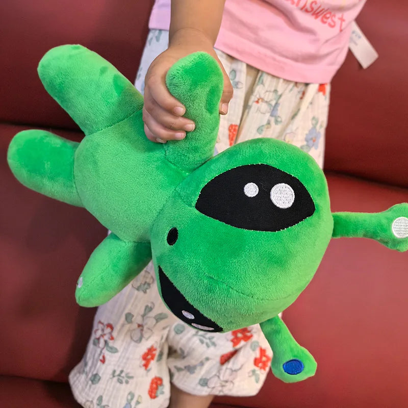 Green alien plush toy held up with arms spread, horn tentacles and black eye patches