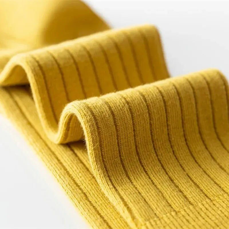 Close-up of mustard yellow ribbed kids knee-high socks with vertical stripe texture.