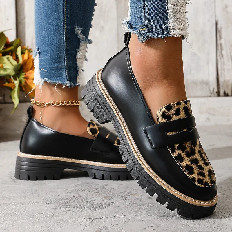 Black loafers with leopard print strap detailing and thick platform sole.