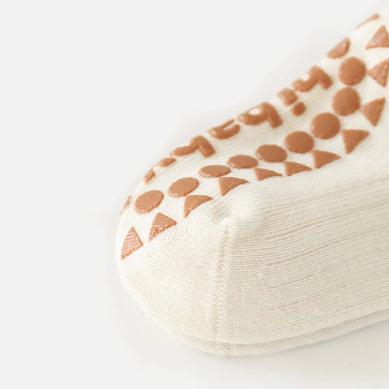 Close-up of kids cotton sock sole: cream fabric with brown non-slip dot grippers