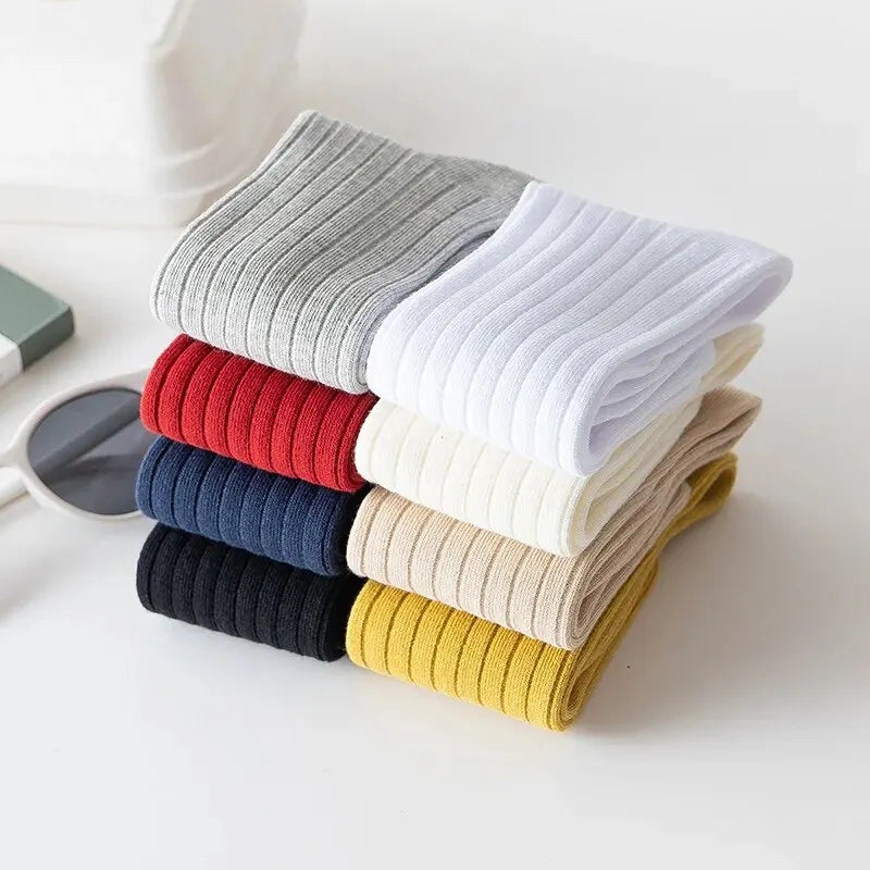 Folded kids knee-high striped socks in black, yellow, red, light gray, white, and beige.