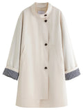 Beige stand-collar windbreaker coat with black-button front and plaid cuff bands