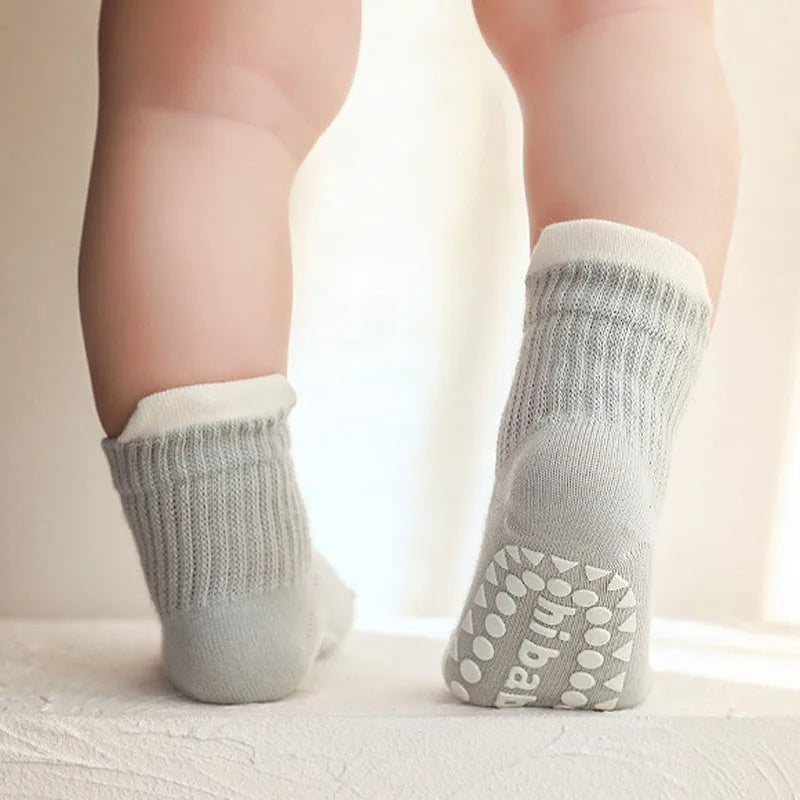 Pair of kids cotton crew socks in light gray with non-slip dot grippers on soles