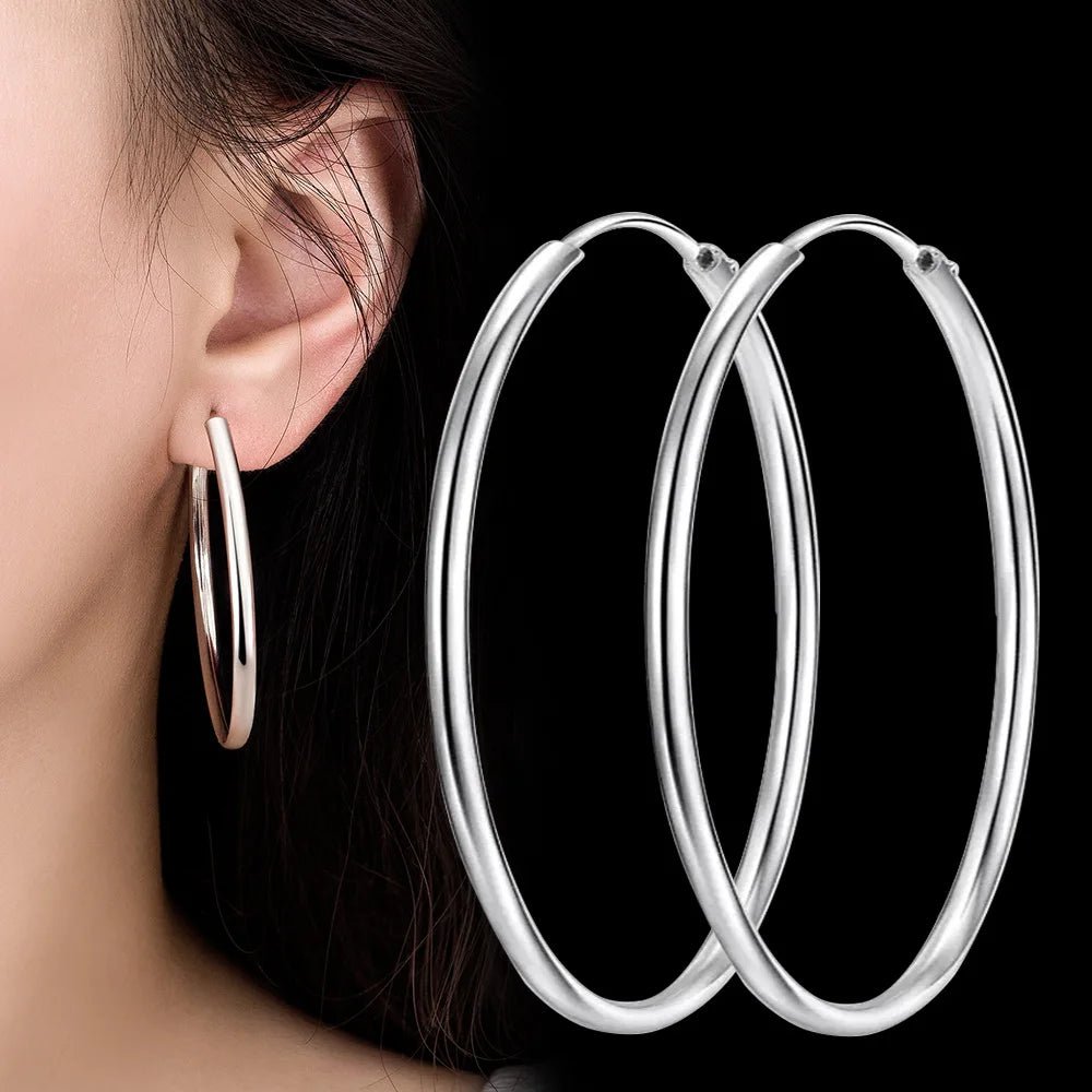 Thick silver hoop earrings on model, large round hoops with polished shine