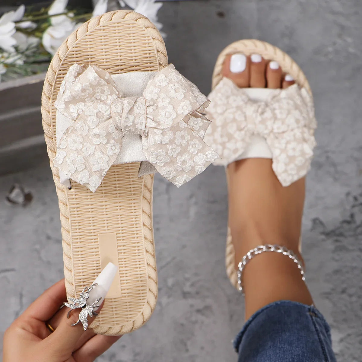Cream lace bow flat slippers on feet with open toe and woven braided sole