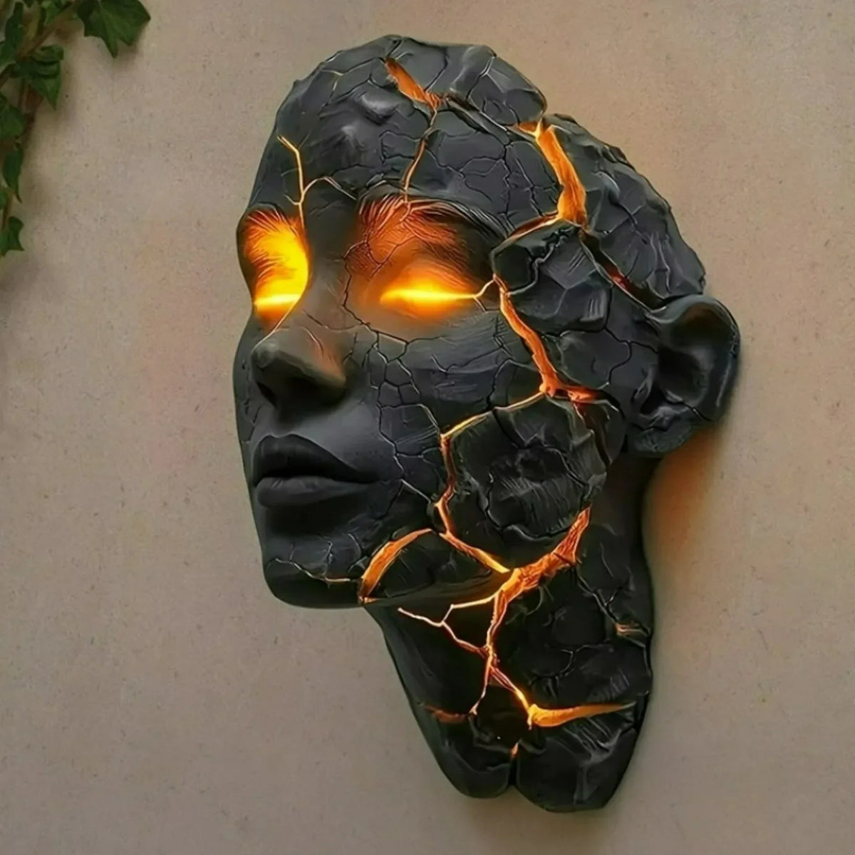 Black resin face wall lamp with glowing orange crack lines and warm light eyes