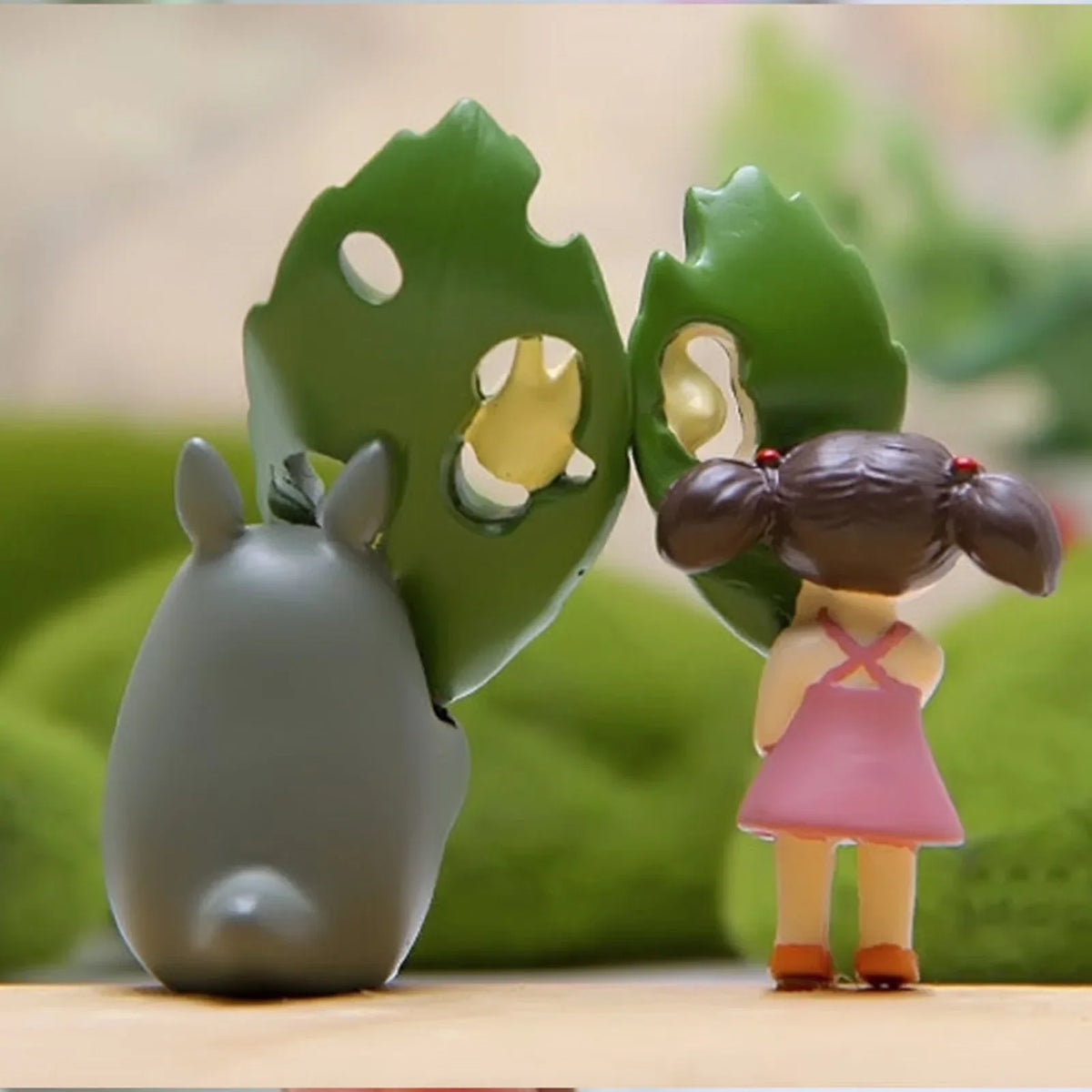 Leaf animal figurine: green leaf face with girl in pink dress and gray critter