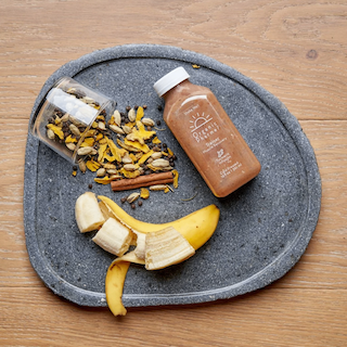 Organic botanical beverage bottle with banana slices and dried herb mix on plate