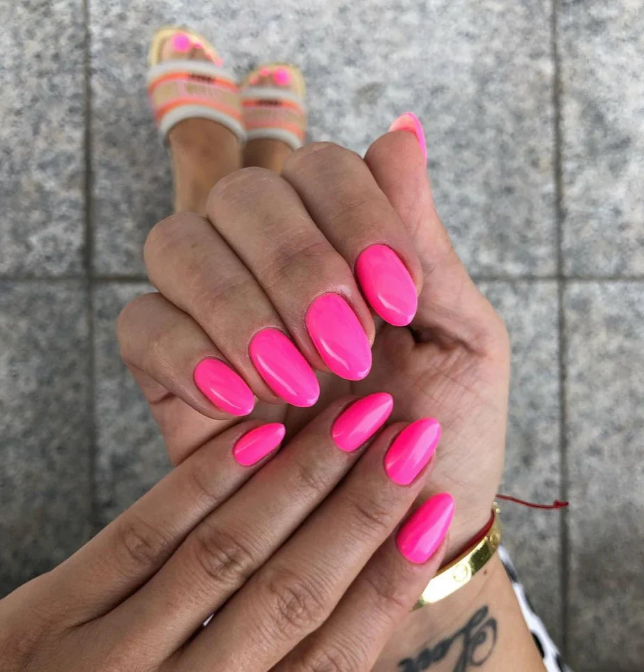 Bright fuchsia gel manicure on fingers with glossy long oval nails