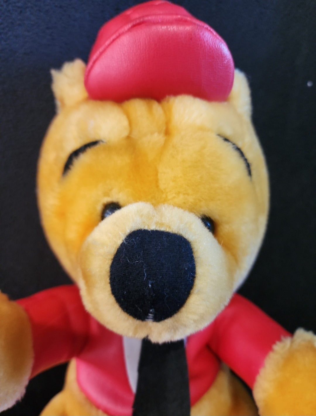 Plush Winnie-the-Pooh bear face close-up in red helmet and racing outfit