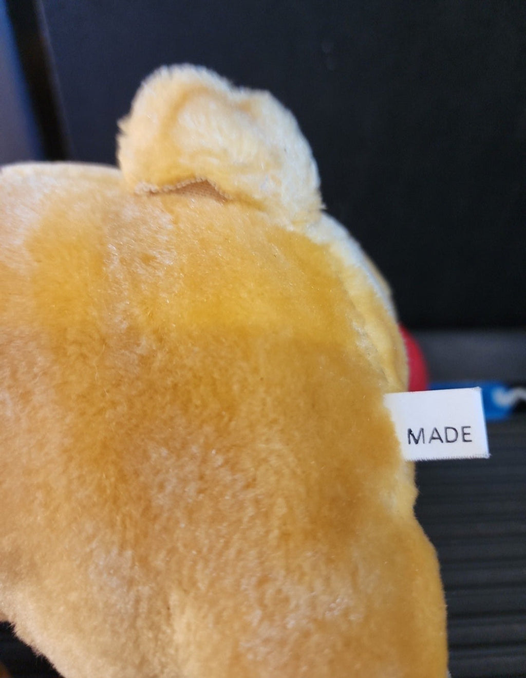 Plush Winnie-the-Pooh bear back with white fabric label reading 'MADE'