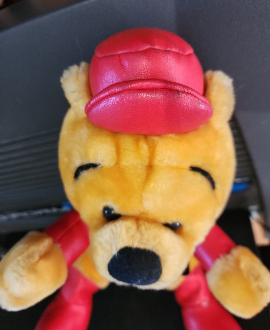 Plush Winnie-the-Pooh bear head-and-shoulders in red helmet and racing outfit