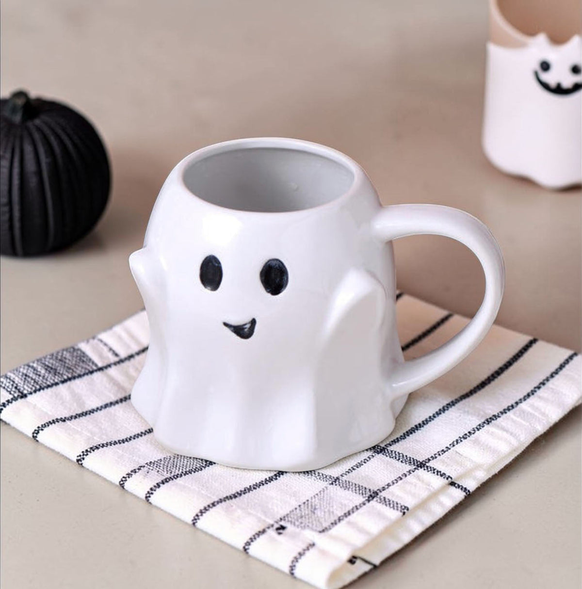 White ghost-shaped ceramic mug with smiling face and curved handle