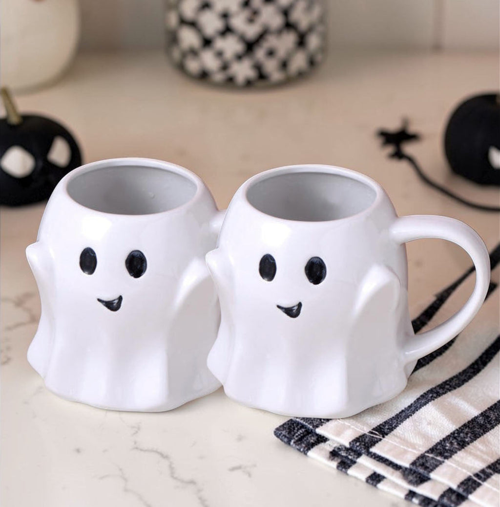 Two white ghost-shaped mugs with black eyes and smiling faces