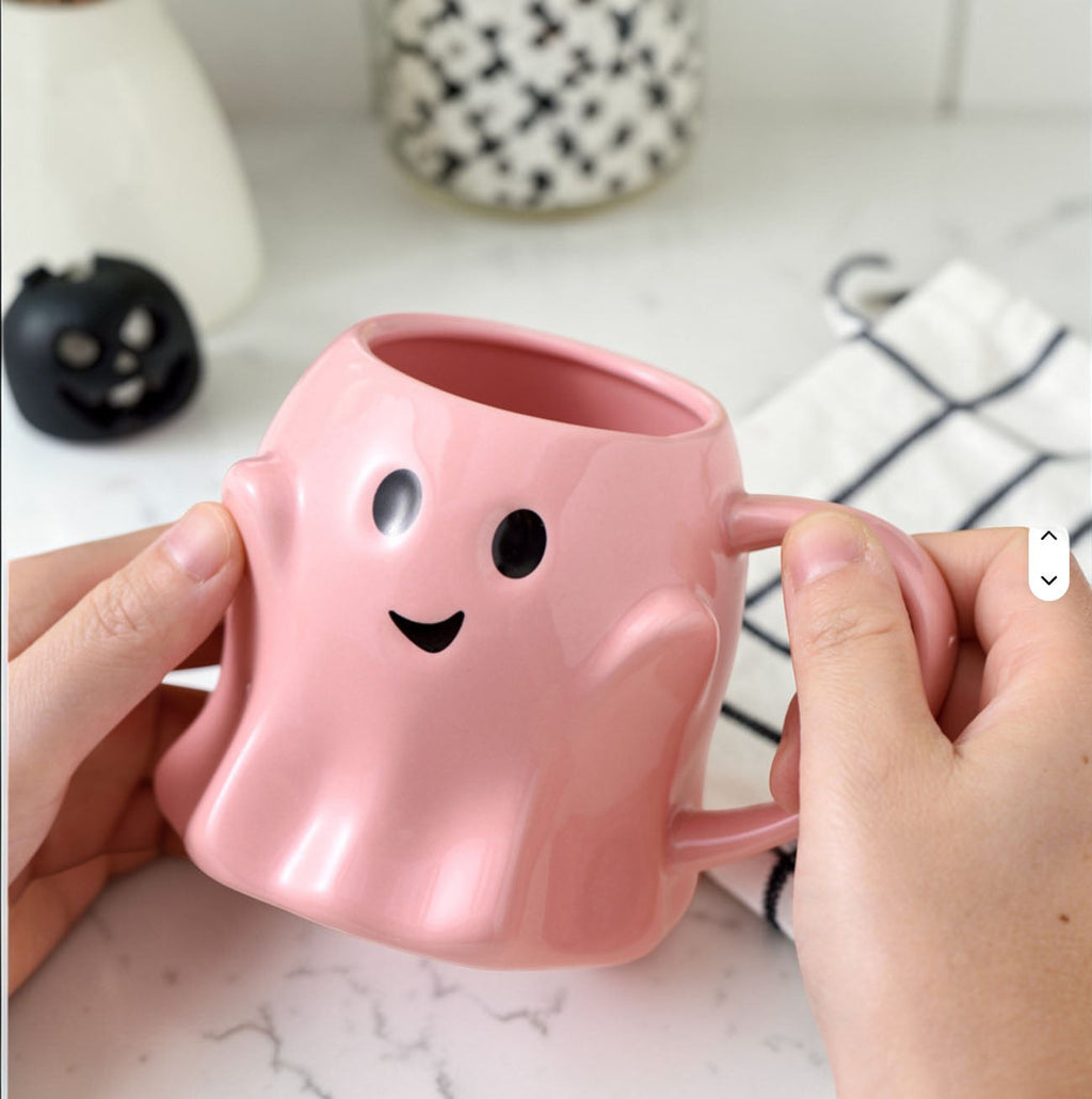 Pink ghost-shaped ceramic mug with rounded ears, smile face, and side handle
