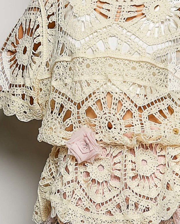 Crochet tie-style belt detail with pink rosette appliques and openwork lace