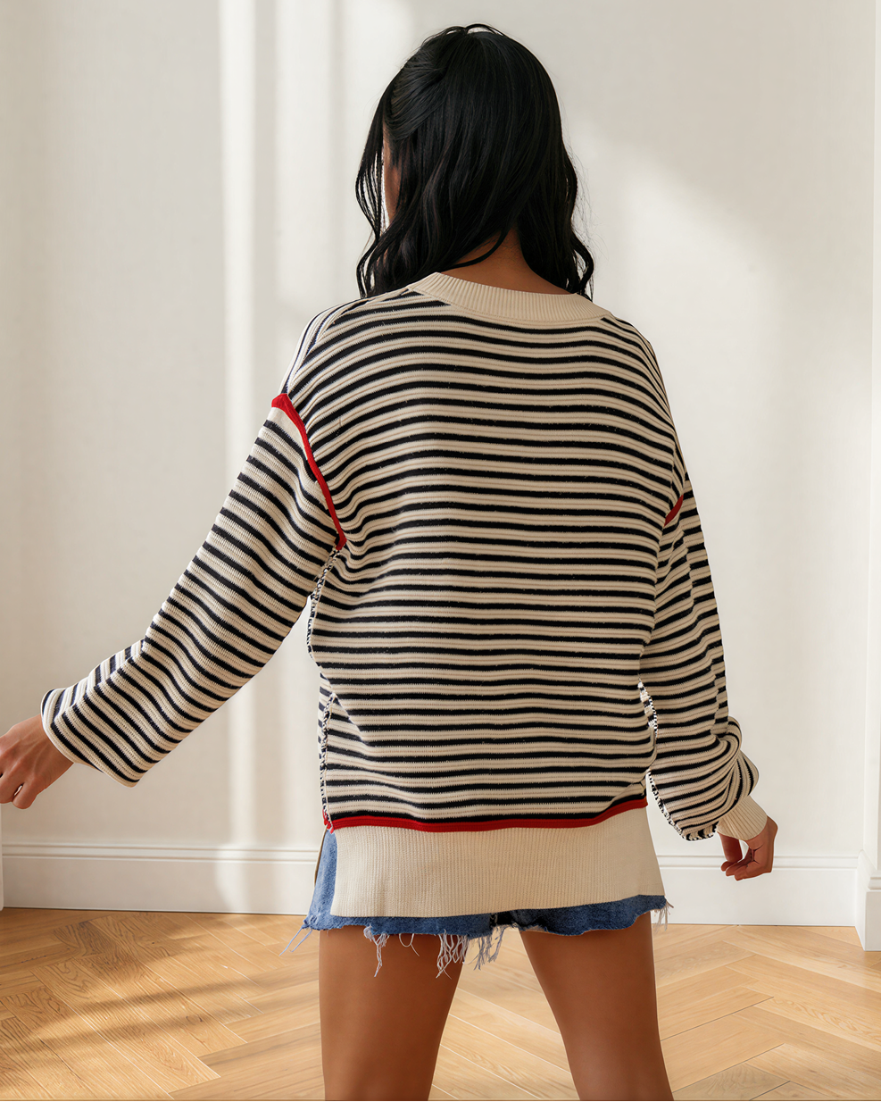 Back view of oversized striped sweater with ribbed crew neck and red trim at cuffs