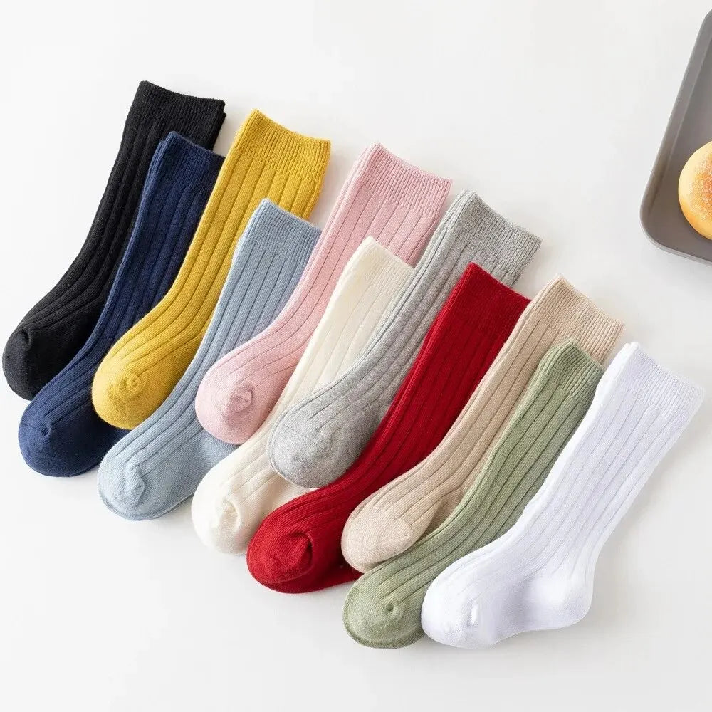 Kids knee-high striped socks in black, navy, mustard, pink, beige, green, and white.