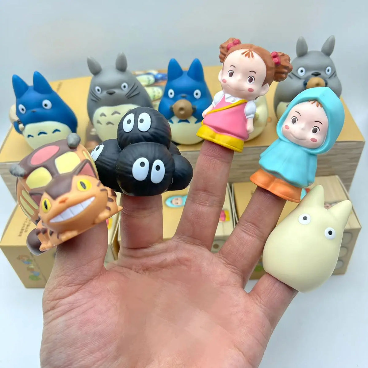 Hand holding assorted cartoon blind box figurines with Totoro-like faces and one tan cat-like toy
