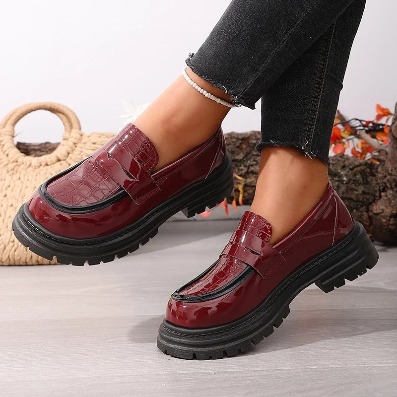 Red patent leather platform loafers with buckle strap, round toe, and thick tread