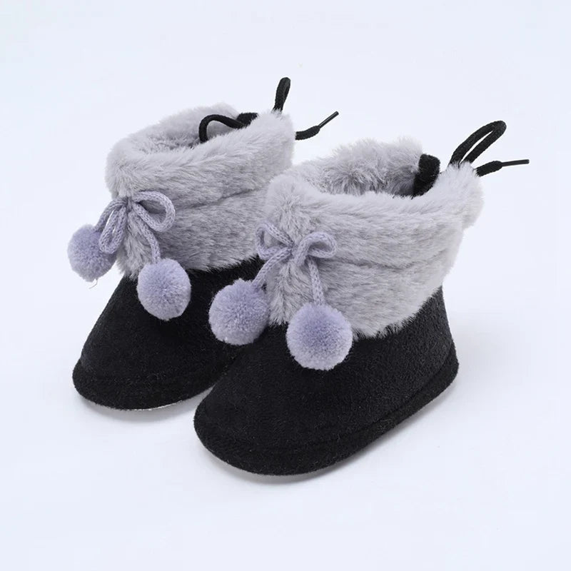 Baby gray and black booties with plush cuffs, bow laces, and pompom accents
