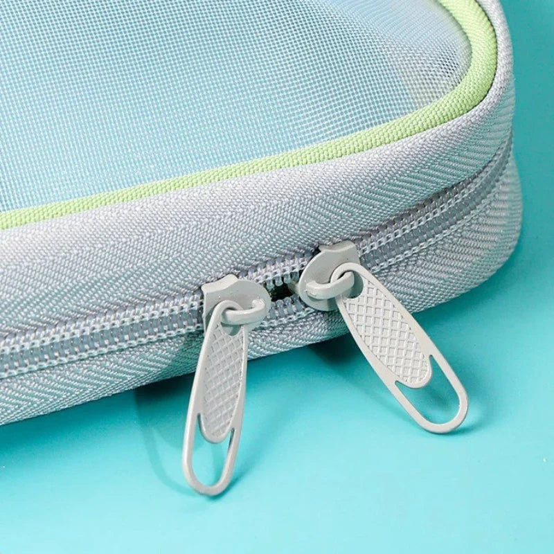 Close-up of double zipper pulls on a mesh stationery storage bag with green edge trim