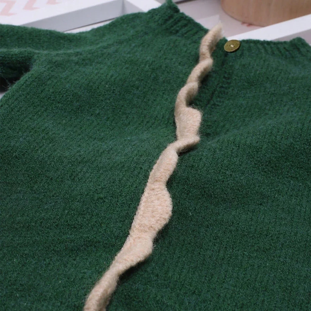 Green knitted dinosaur jumpsuit close-up: buttoned neckline and beige trim