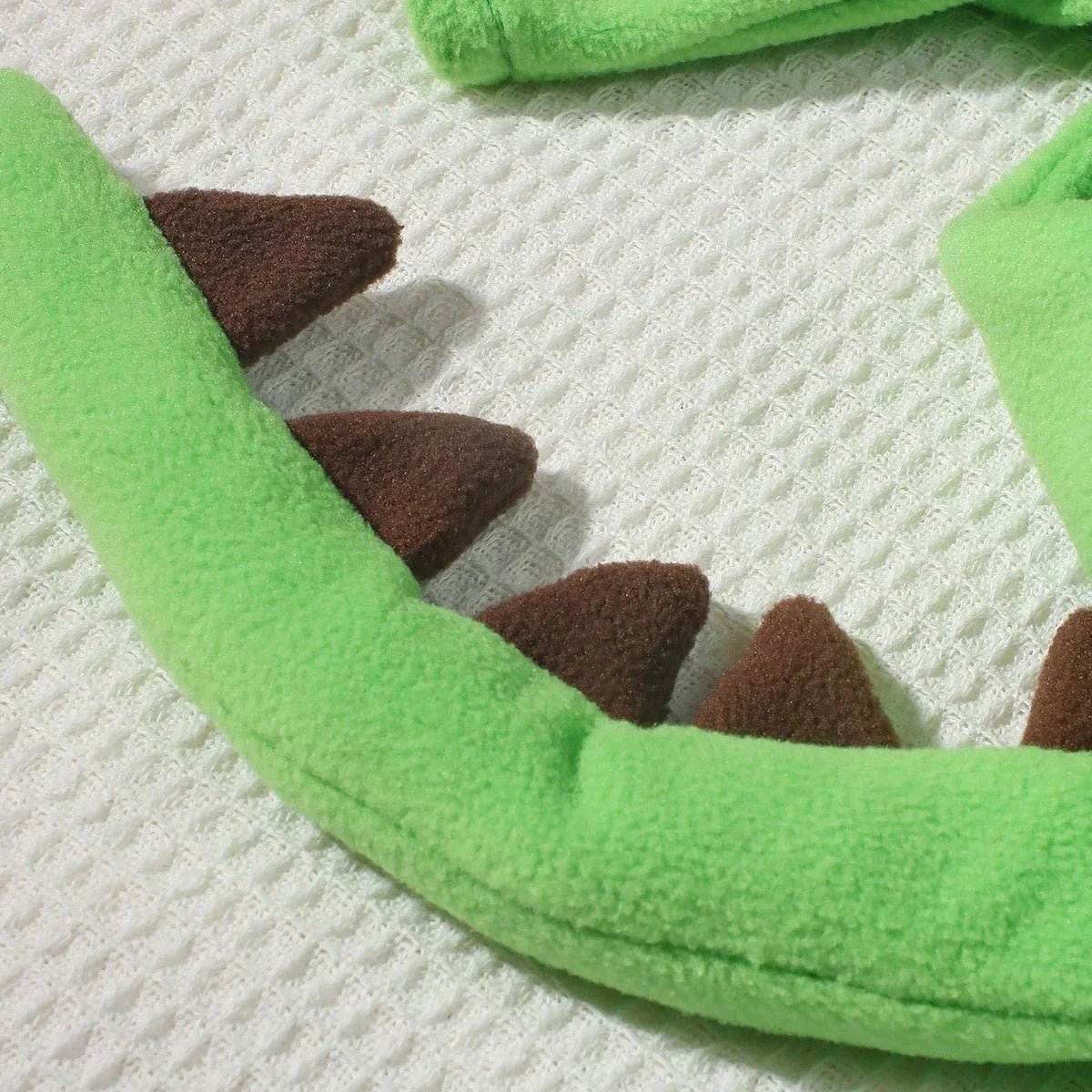 Green dinosaur costume hood curve with brown fabric spikes along edge