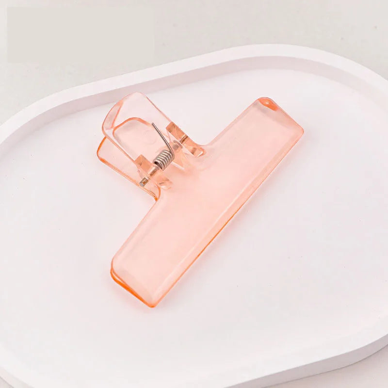 Orange ice jelly clip with transparent acrylic body and spring clasp on tray
