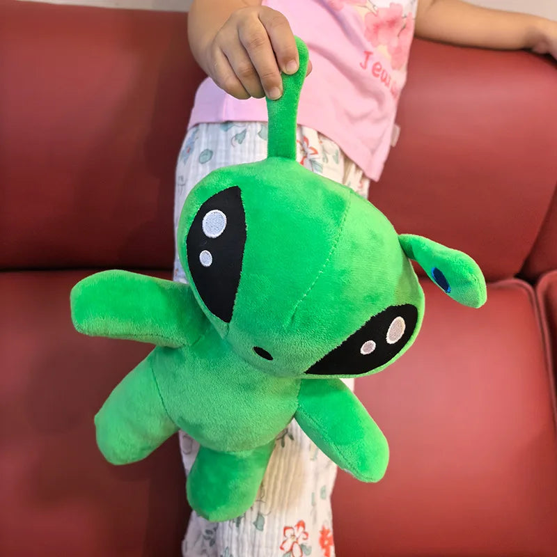 Green alien plush toy held on couch, side view of horn tentacles and smiling face