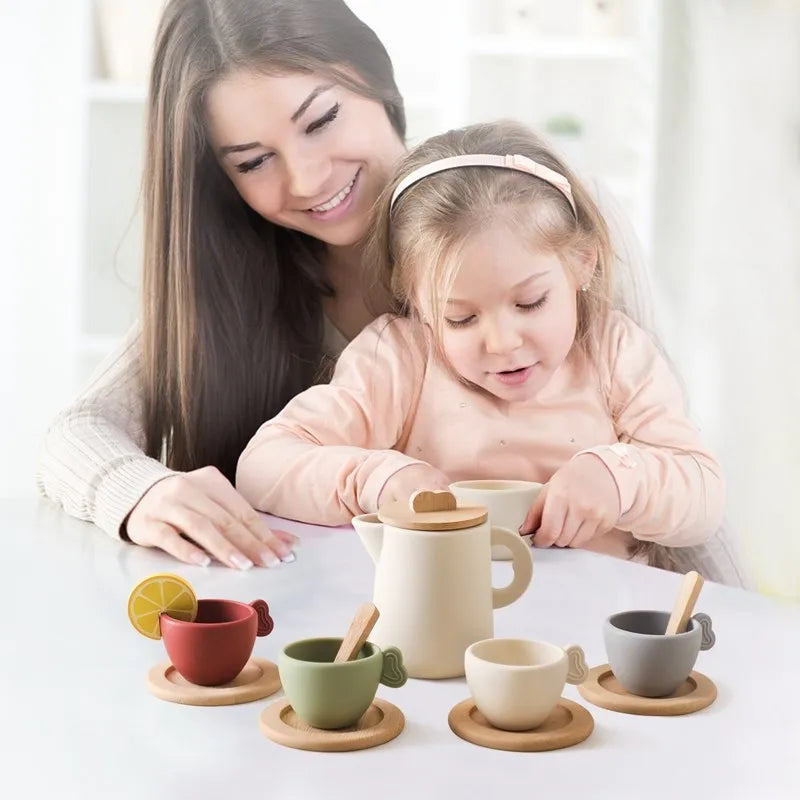 Toddler wooden tea set with white teapot and colorful cups on round wooden tray