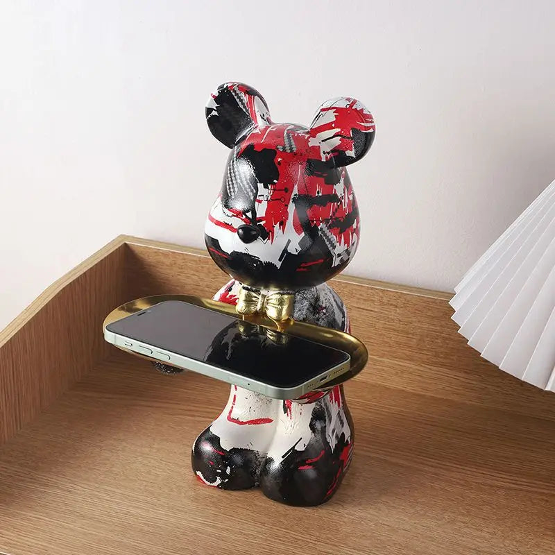 Red-and-white graffiti resin bear desk organizer with gold tray holding a phone