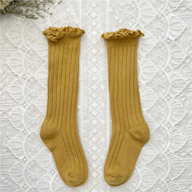 Knee-high ruffle socks with lace cuff, mustard yellow pair laid flat